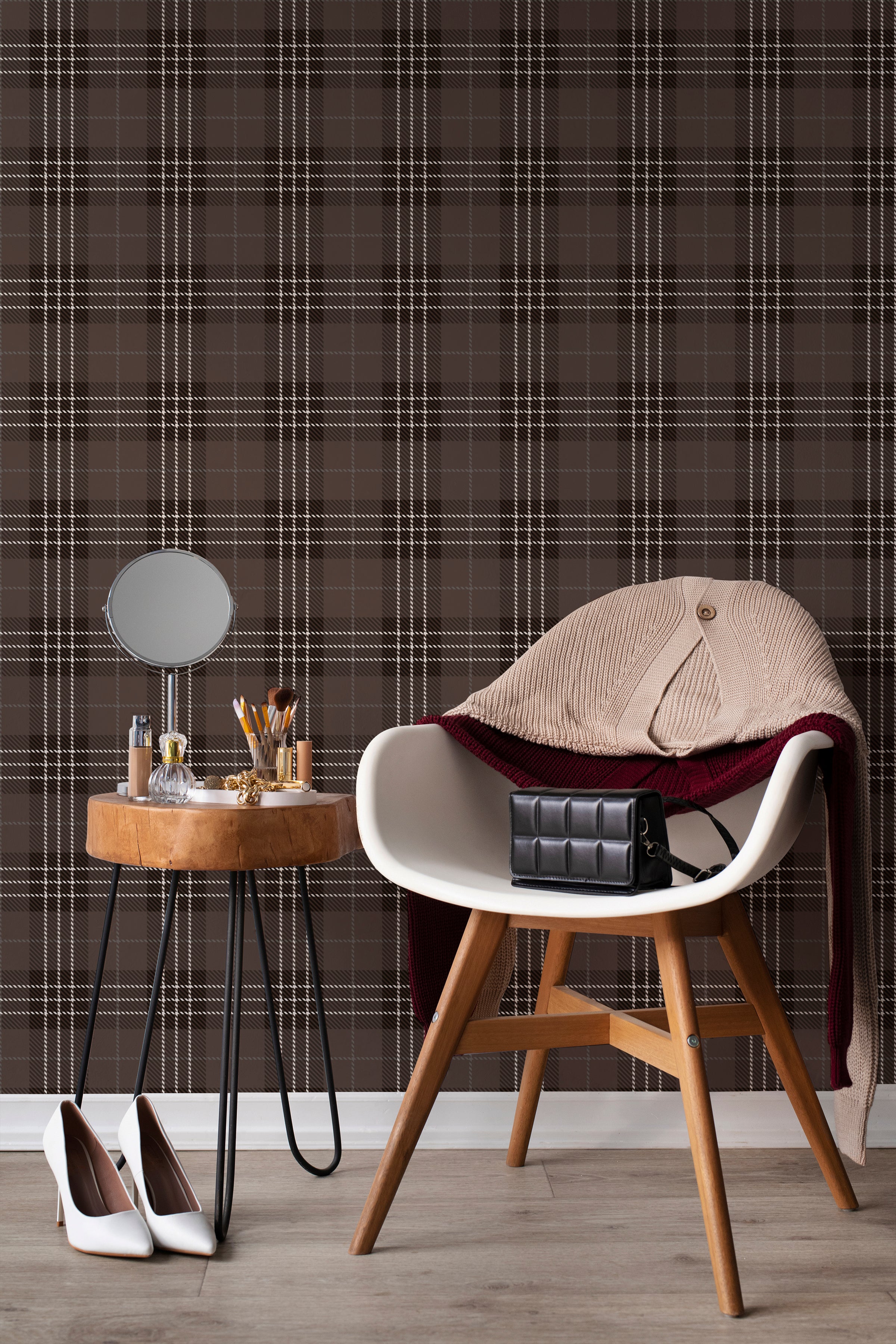 An elegant interior setting where Dark Plaid Wallpaper - Black serves as a backdrop, exuding a classic, sophisticated charm. The scene includes a stylish mid-century modern chair draped with a knit sweater and a purse, a side table with personal items and a round mirror, creating a personal vanity space.