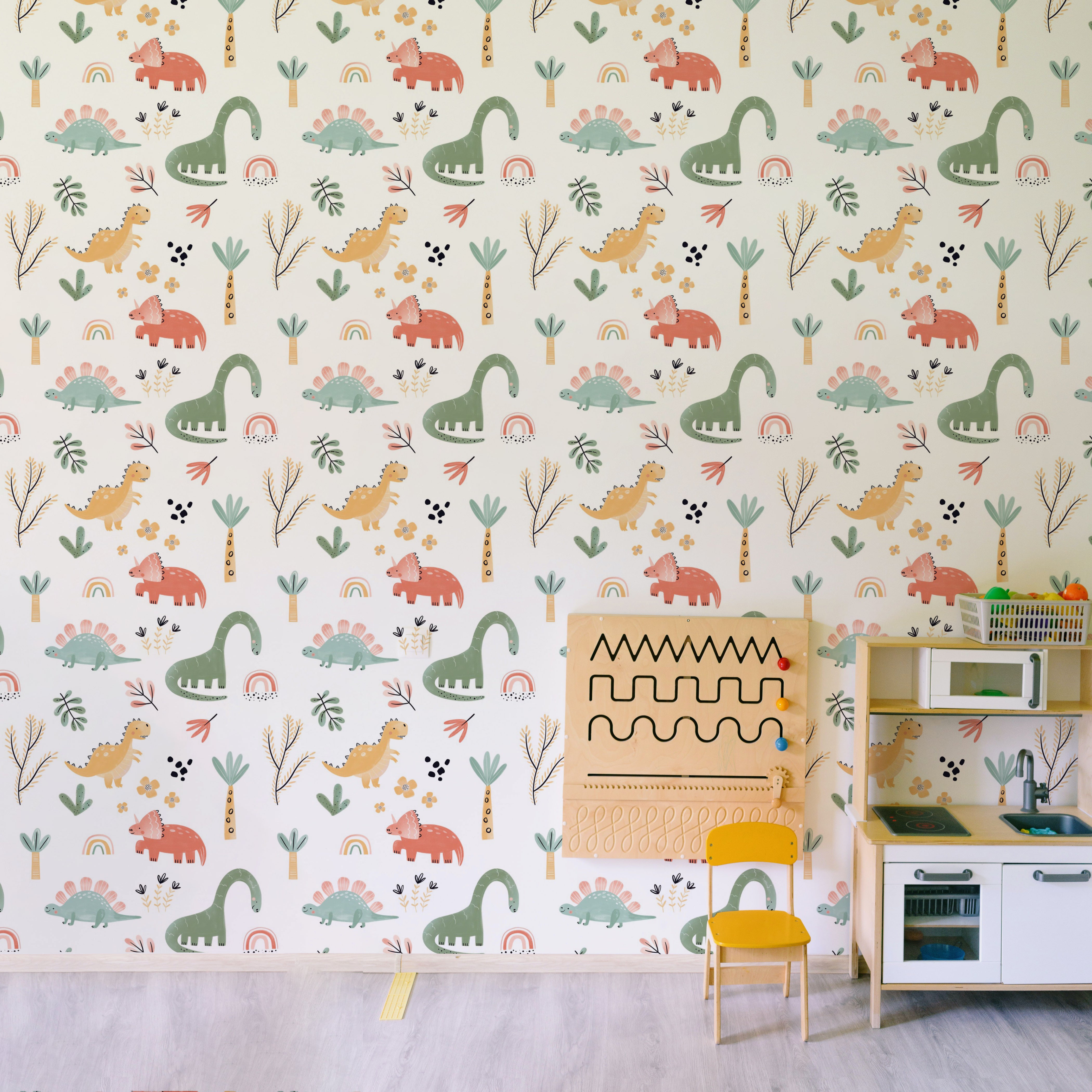 A well-lit nursery corner showcasing the Dinosaur Nursery Wallpaper as a delightful backdrop to a modern play kitchen, with dinosaur and nature motifs scattered in soft, playful hues, inspiring imagination and adventure in any child's room.