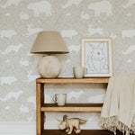 A home office with a light wooden desk and white chair placed against a warm beige wallpaper adorned with white woodland animals including bears, foxes, and rabbits, creating a calming and natural ambiance
