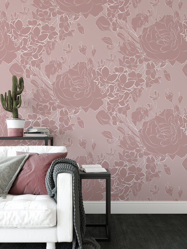 A modern bedroom featuring the Dusty Rose Floral Wallpaper, with soft pink walls adorned with white floral designs. The decor includes a white sofa bed, gray throw blankets, and a minimalist black bedside table, creating a tranquil and stylish ambiance.