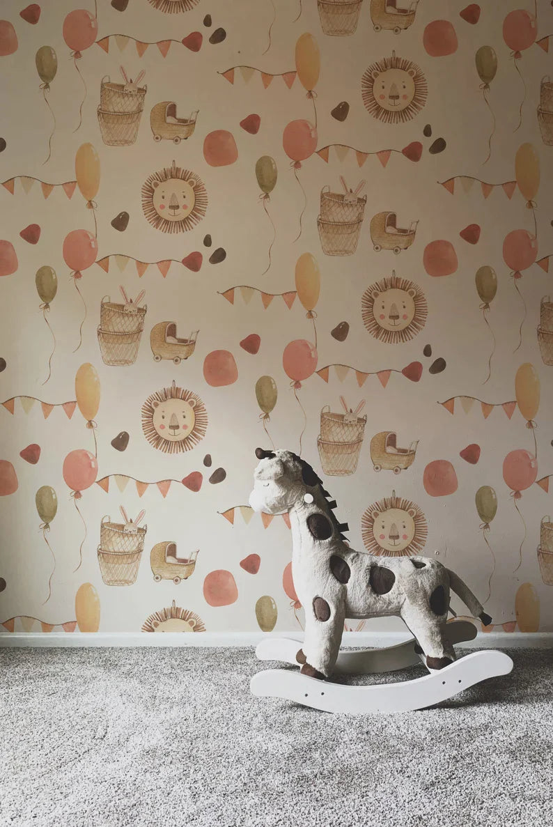 A cozy corner of a nursery showing a part of the wall decorated with a cute, animal-themed wallpaper. Visible motifs include lions' faces, balloons, and bunting flags, complemented by a soft plush rocking giraffe in the foreground, enhancing the playful, child-friendly decor.