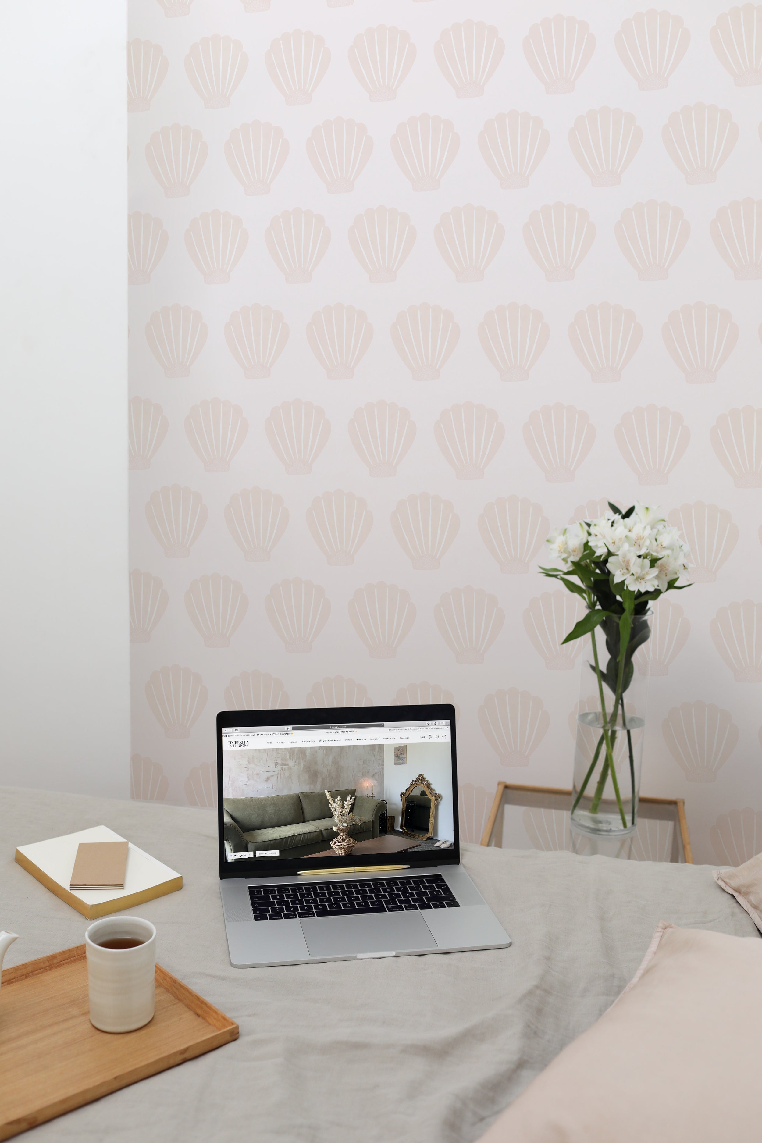 A home office setup with Mermaid Sea Shell wallpaper creating a calm and inviting workspace. The desk features a laptop, notebooks, and a vase of fresh flowers, enhancing productivity in a stylish environment