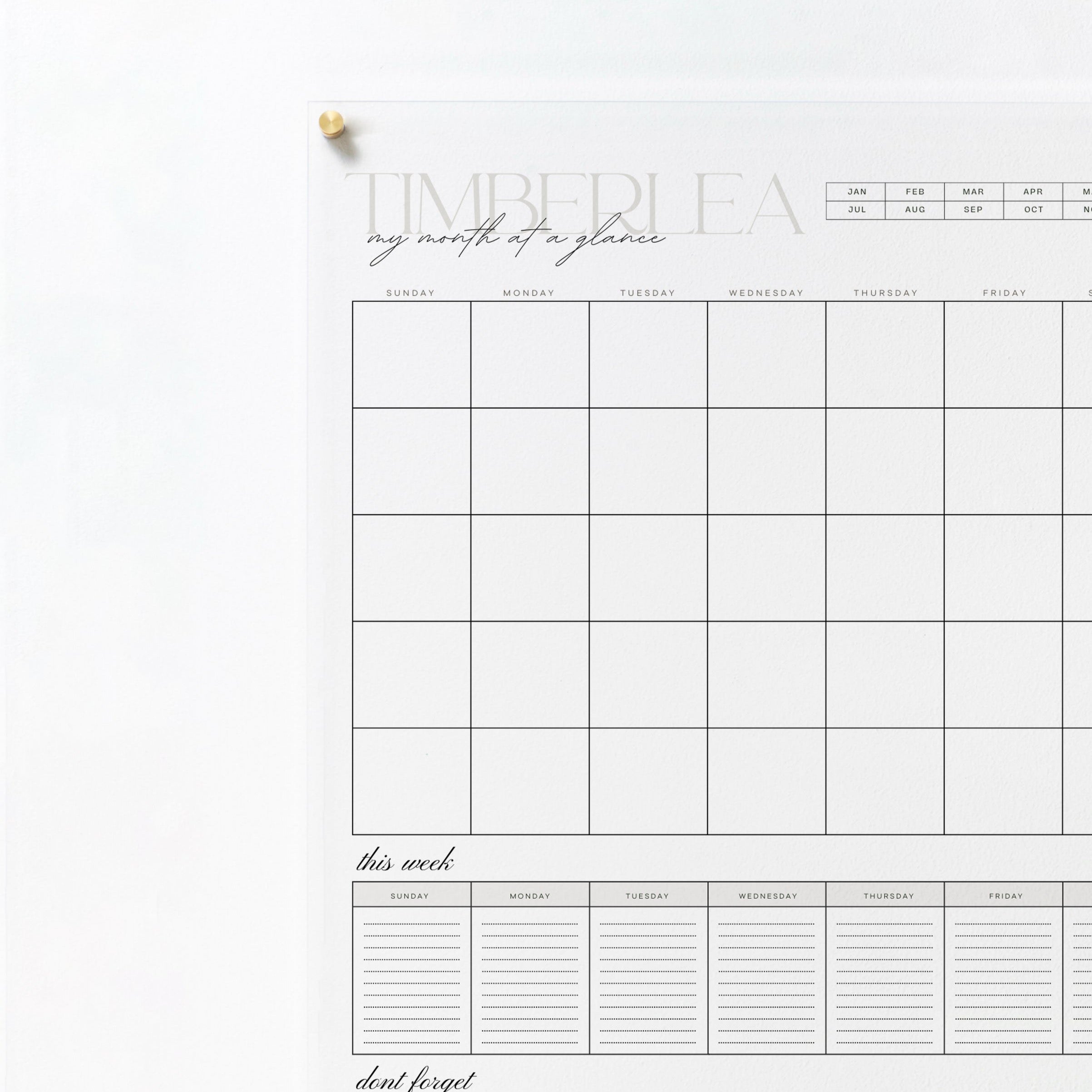 A close-up view of the top left corner of the same acrylic board, showing the calendar's heading and the beginning of the monthly grid. The board is mounted on a wall with a gold pin.