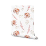 A roll of pastel watercolor floral wallpaper unrolled to display its full pattern. The wallpaper features soft peach and pink roses, baby's breath, and light coral leaves against a clean white backdrop.