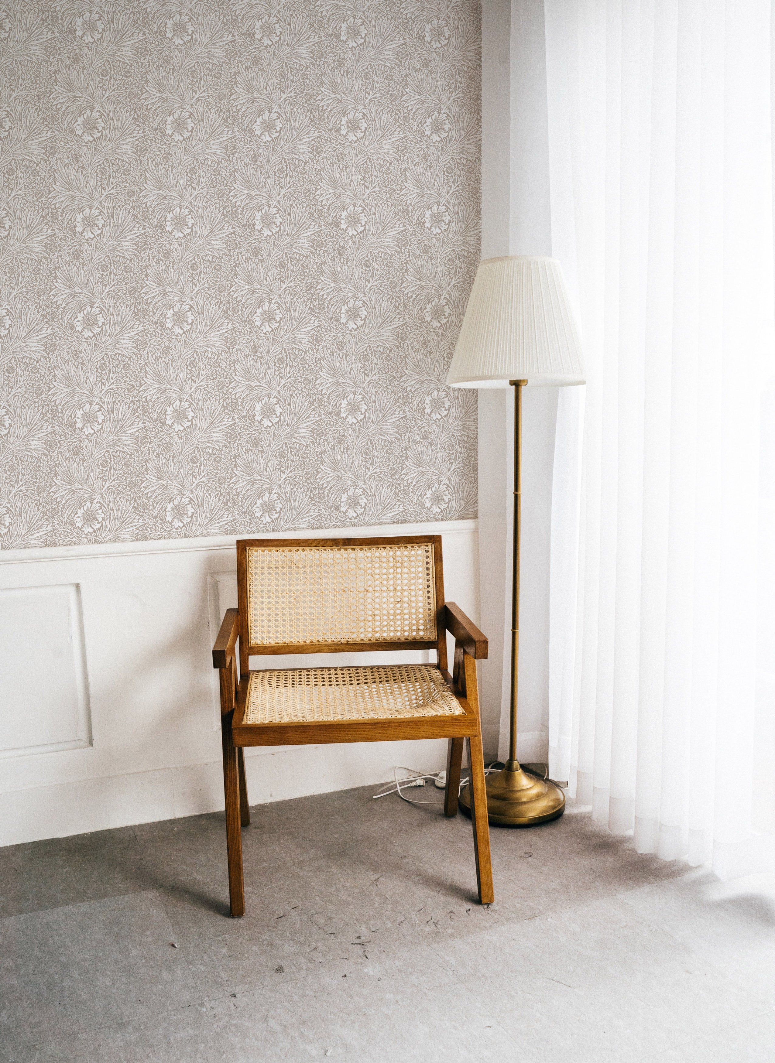 Minimalistic and serene workspace accentuated by Timeless Floral Wallpaper with delicate beige floral motifs, paired with a simple wooden chair and floor lamp