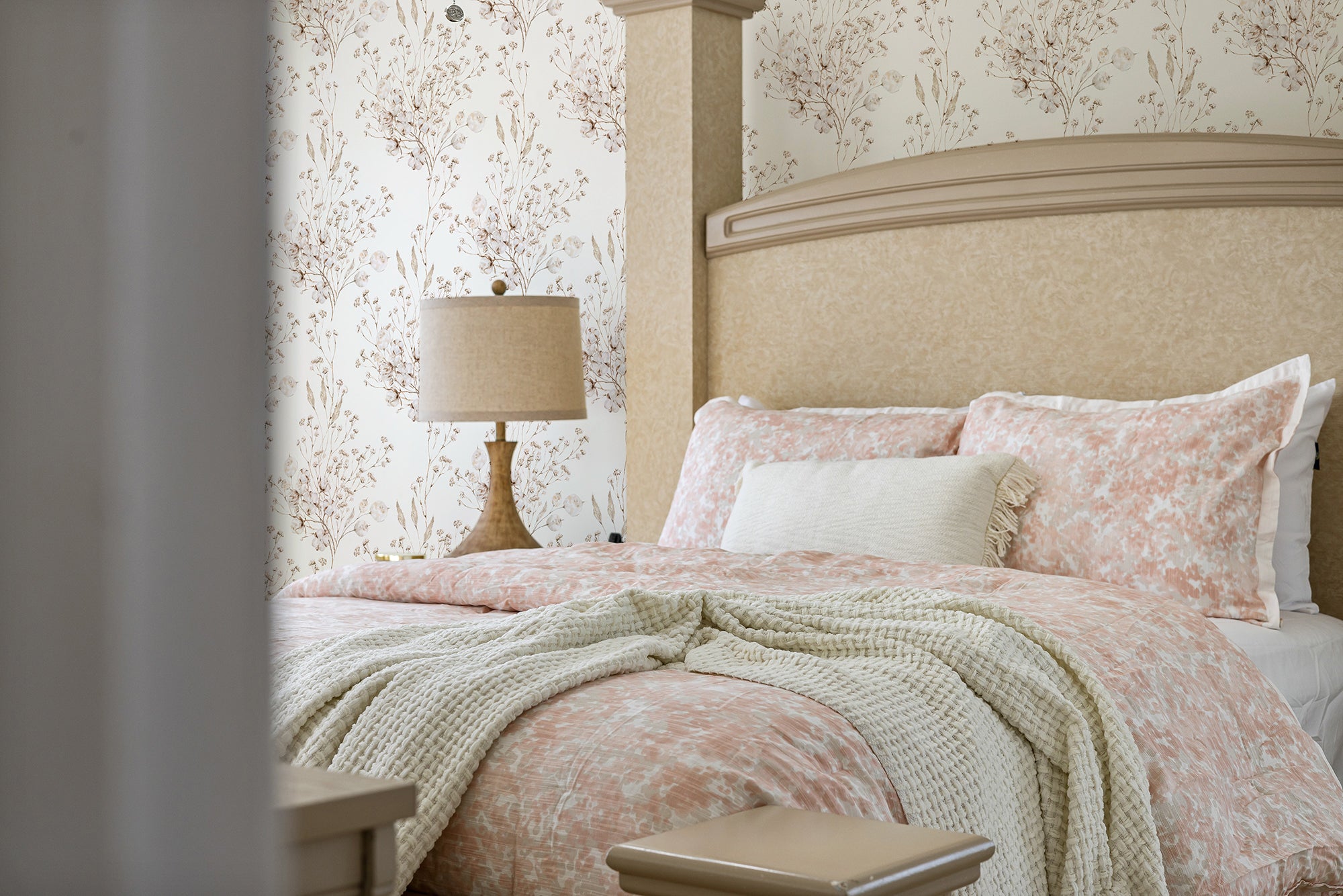 A bedroom beautifully decorated with the Boho Winter Floral Wallpaper, creating a soothing ambiance. The wallpaper pairs perfectly with light pink bedding and a knitted throw, emphasizing a warm and inviting winter atmosphere.