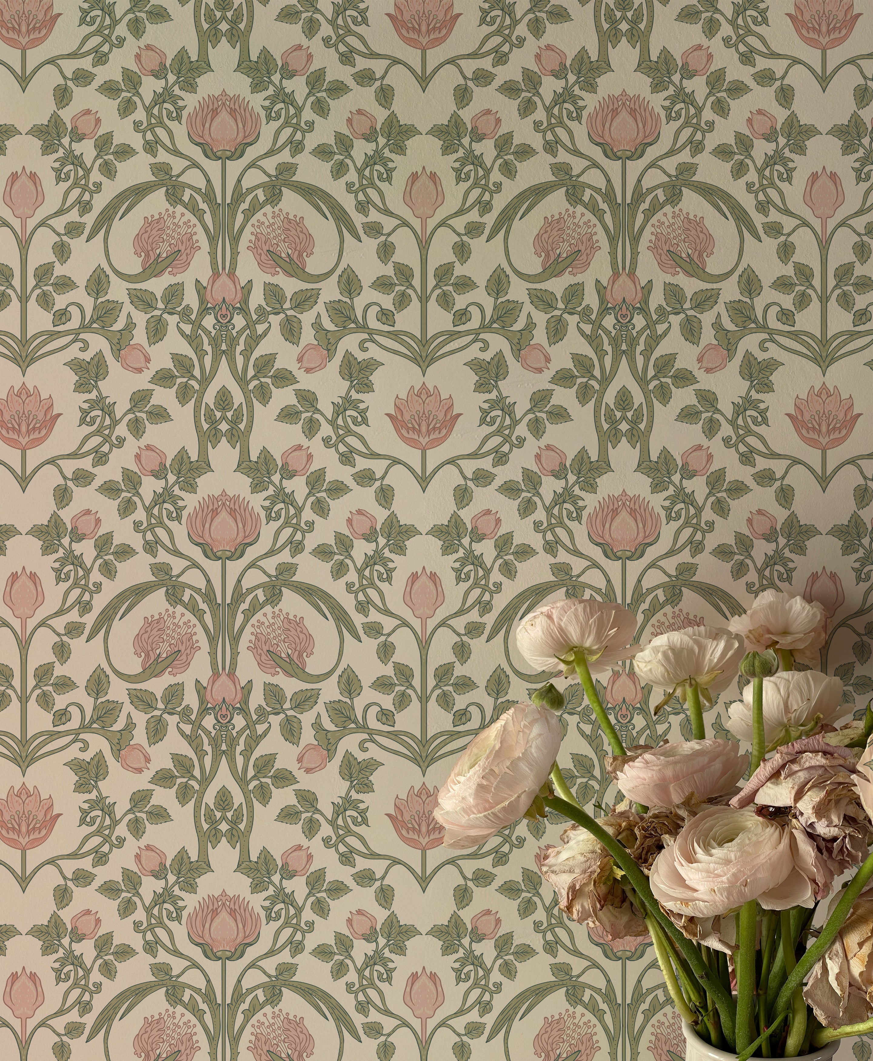 A close-up of a vase holding a variety of pale pink flowers, with the detailed pattern of the pastel floral damask wallpaper filling the frame