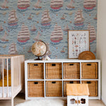 A nursery decorated with Breezy Sail Wallpaper, displaying a rich texture and colorful sailboats that enhance the room's cozy and imaginative atmosphere. The room includes a crib and a wicker basket storage unit.