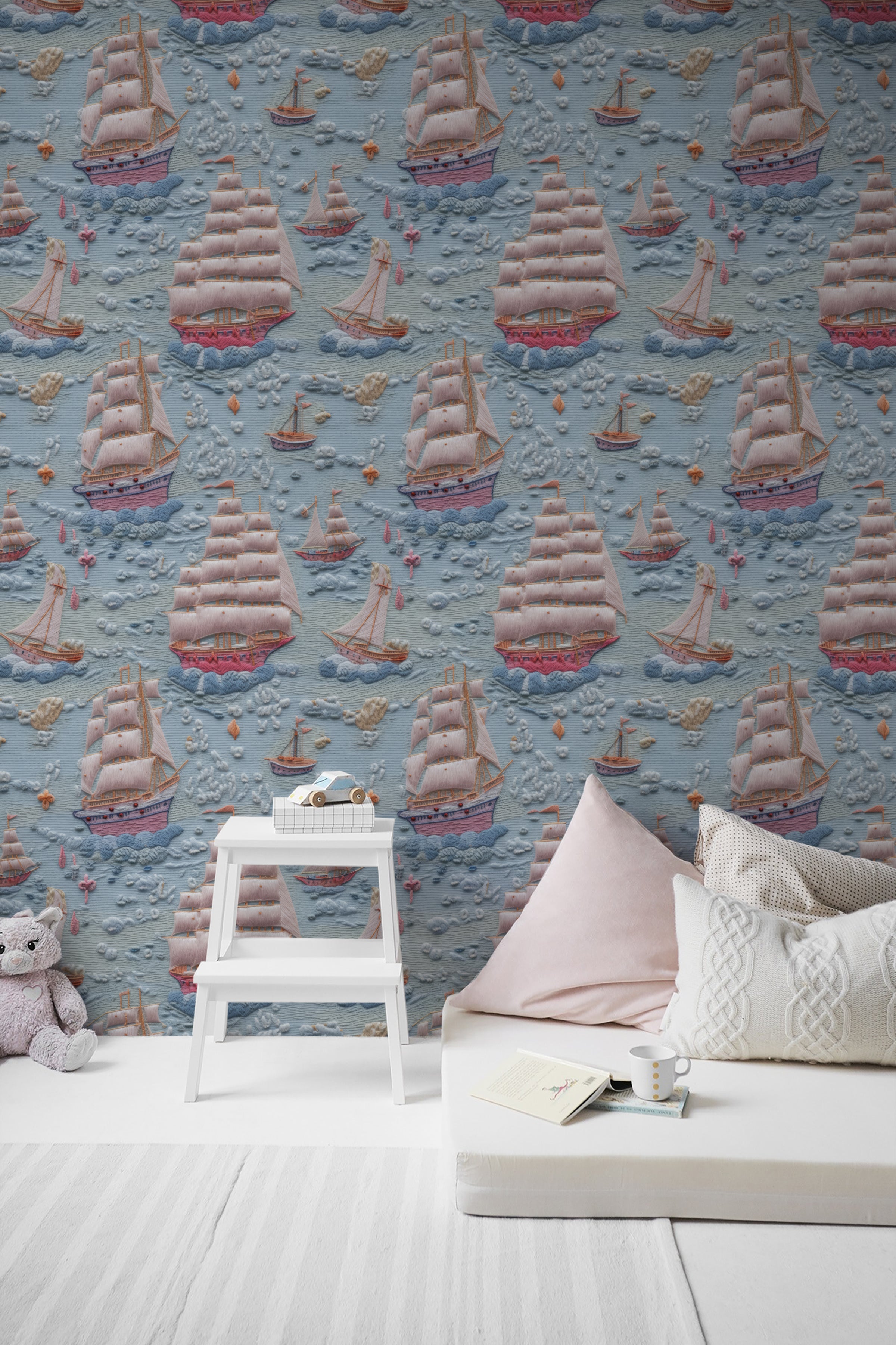 Children's room featuring Breezy Sail Wallpaper with a playful pattern of large sailboats on a textured blue background, styled with a white step stool and plush toys, creating a whimsical maritime theme.