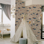 A child's play area decorated with Windward Sail Wallpaper, featuring a whimsical pattern of white sailboats with red and blue accents on a textured beige background. The setting includes a playful tent and soft, inviting colors, enhancing the nautical theme.