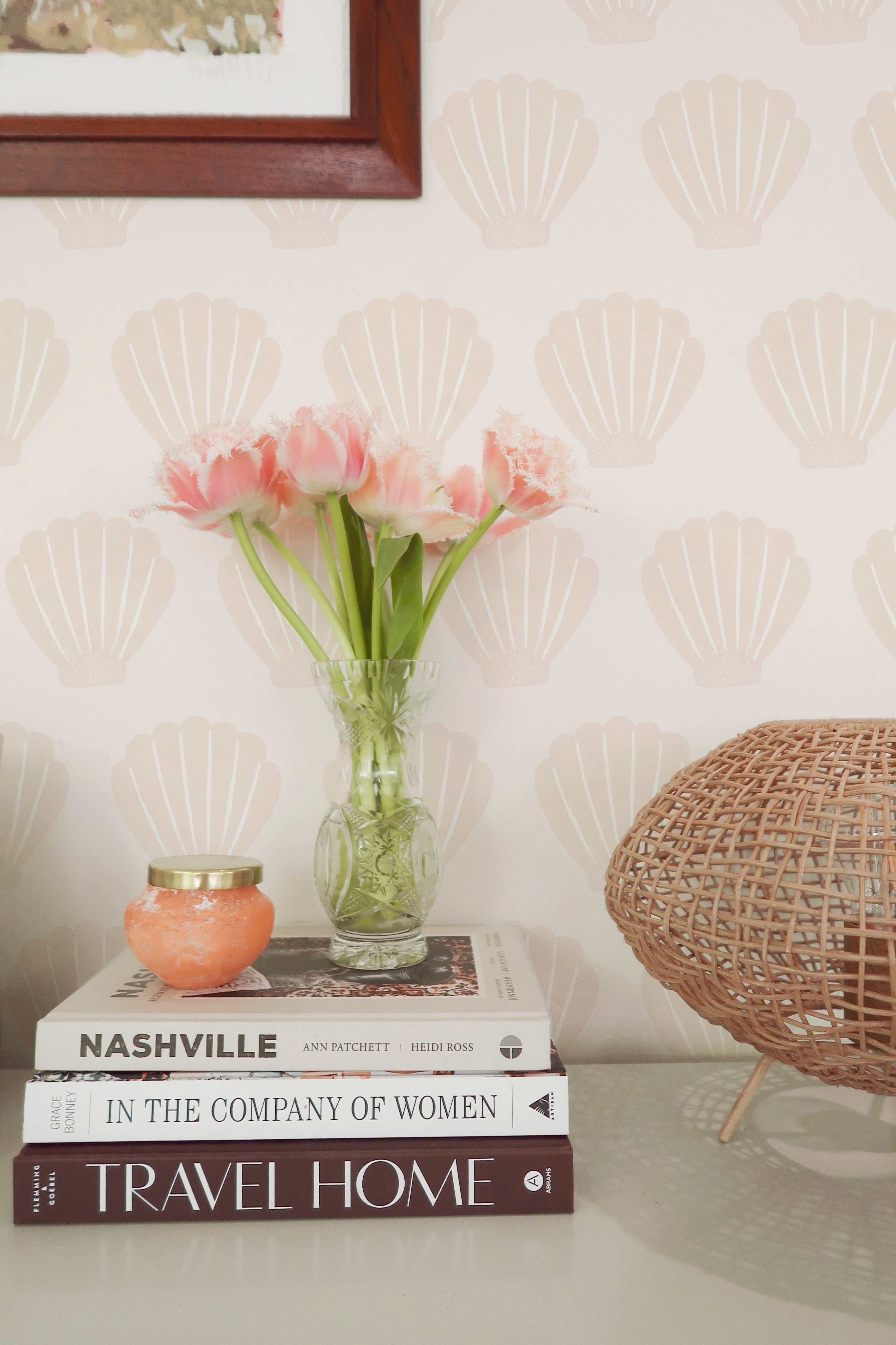 A cozy reading nook with Mermaid Sea Shell wallpaper providing a charming backdrop. The scene includes a wooden chair, a pile of books, and fresh flowers, creating a perfect spot for reading and relaxation.