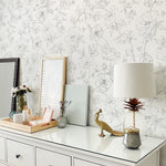 Stylish dresser against Dainty Floral Line Wallpaper, adorned with a variety of modern decorations and a lamp.