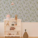 Interior view of a children's playroom with Simple Floral Wallpaper - 25" on the feature wall. The wallpaper features a delicate pattern of small white flowers and green leaves on a soft blue background, creating a whimsical and inviting atmosphere.