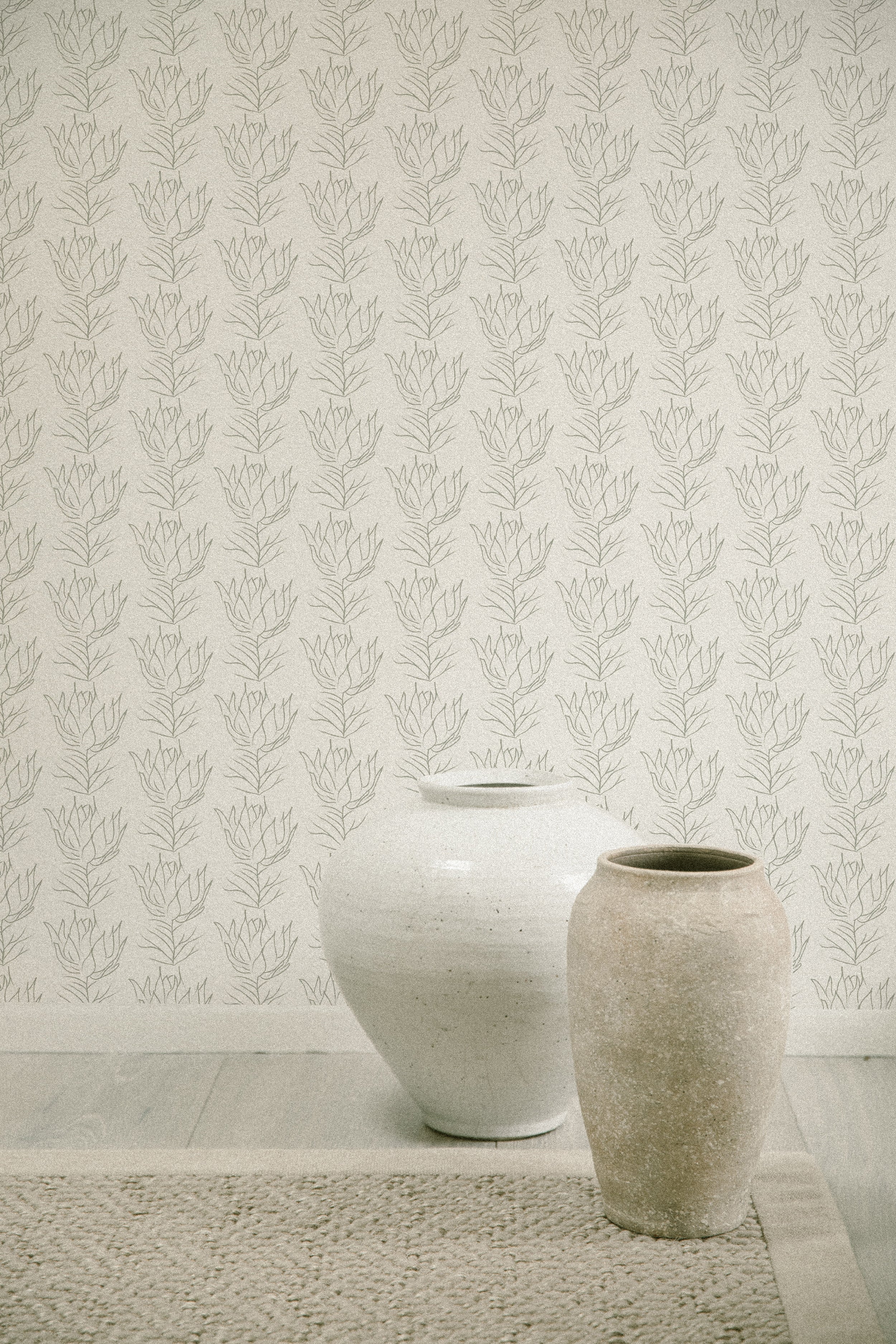 A neutral-toned interior featuring the Line Art Bouquet Wallpaper, with a delicate pattern of sketched floral bouquets in a repetitive arrangement, accompanied by two earthenware vases on a woven mat, invoking a sense of artisanal elegance.