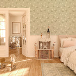 Interior view of a child's bedroom with Soft Meadow Wallpaper - 25" on the feature wall. The wallpaper displays a charming pattern of small white flowers and green foliage on a soft sage background, enhancing the room's cozy and playful decor.