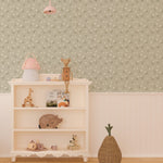 Interior view of a nursery with Soft Meadow Wallpaper - 12.5" on the feature wall. The wallpaper displays a subtle pattern of white flowers and green foliage on a soft sage background, enhancing the room's cozy and playful decor.