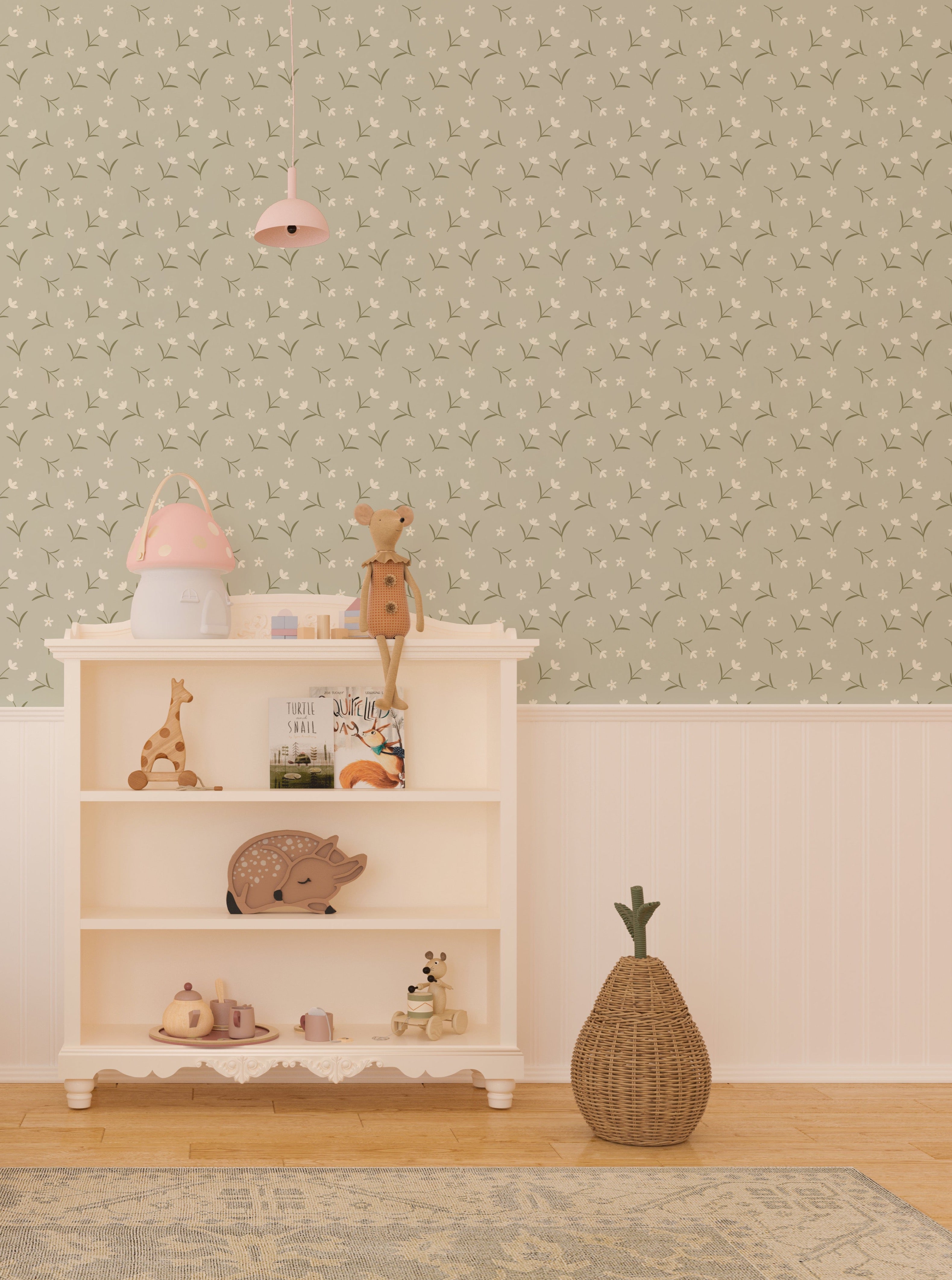 Interior view of a nursery with Soft Meadow Wallpaper - 12.5" on the feature wall. The wallpaper displays a subtle pattern of white flowers and green foliage on a soft sage background, enhancing the room's cozy and playful decor.
