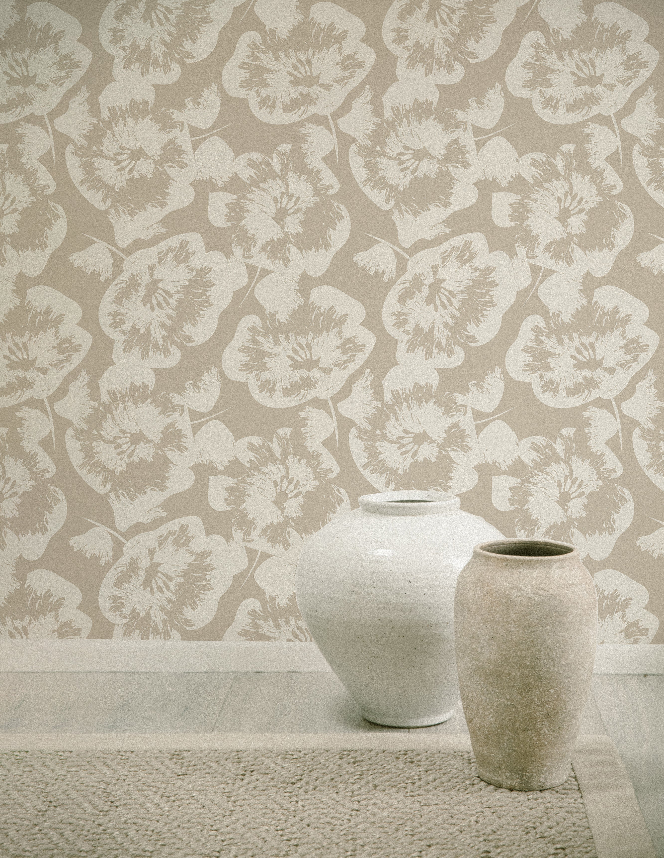 A contemporary room featuring Stamped Floral Wallpaper, with large beige flowers on a lighter background creating a bold yet elegant pattern. The decor includes two textured ceramic vases on a wooden floor, complementing the wallpaper's organic aesthetic