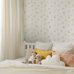 A serene bedroom showcasing Sunny Floral Wallpaper with subtle floral patterns, complementing the soft bedding and cuddly stuffed animals resting on the bed