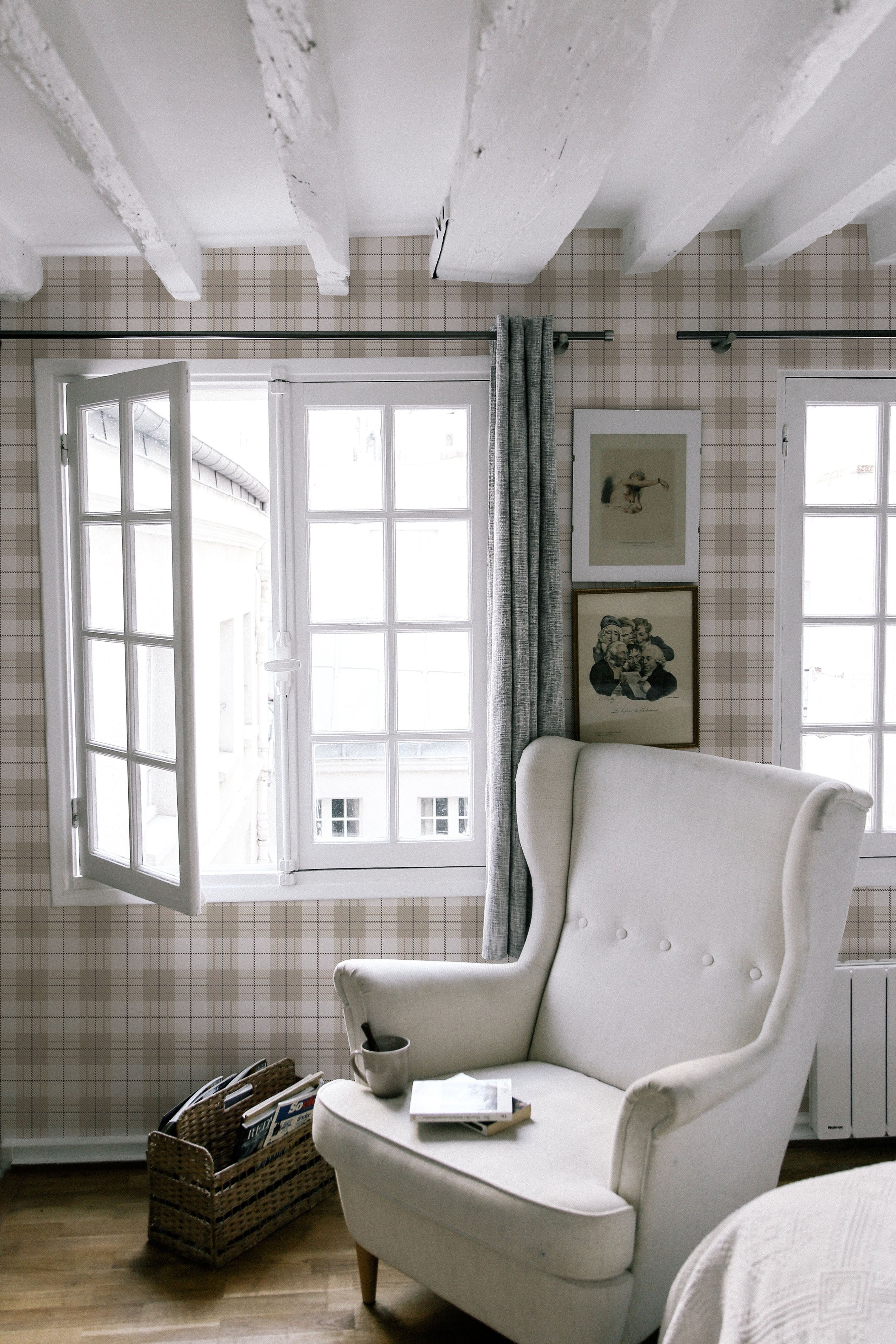 A cozy reading nook illuminated by natural light from large windows, with an elegant wingback chair set against the Winter Plaid Wallpaper. The room's plaid-patterned walls give a feeling of comfort and nostalgia, enhanced by the room's rustic wooden floors and classic decor.