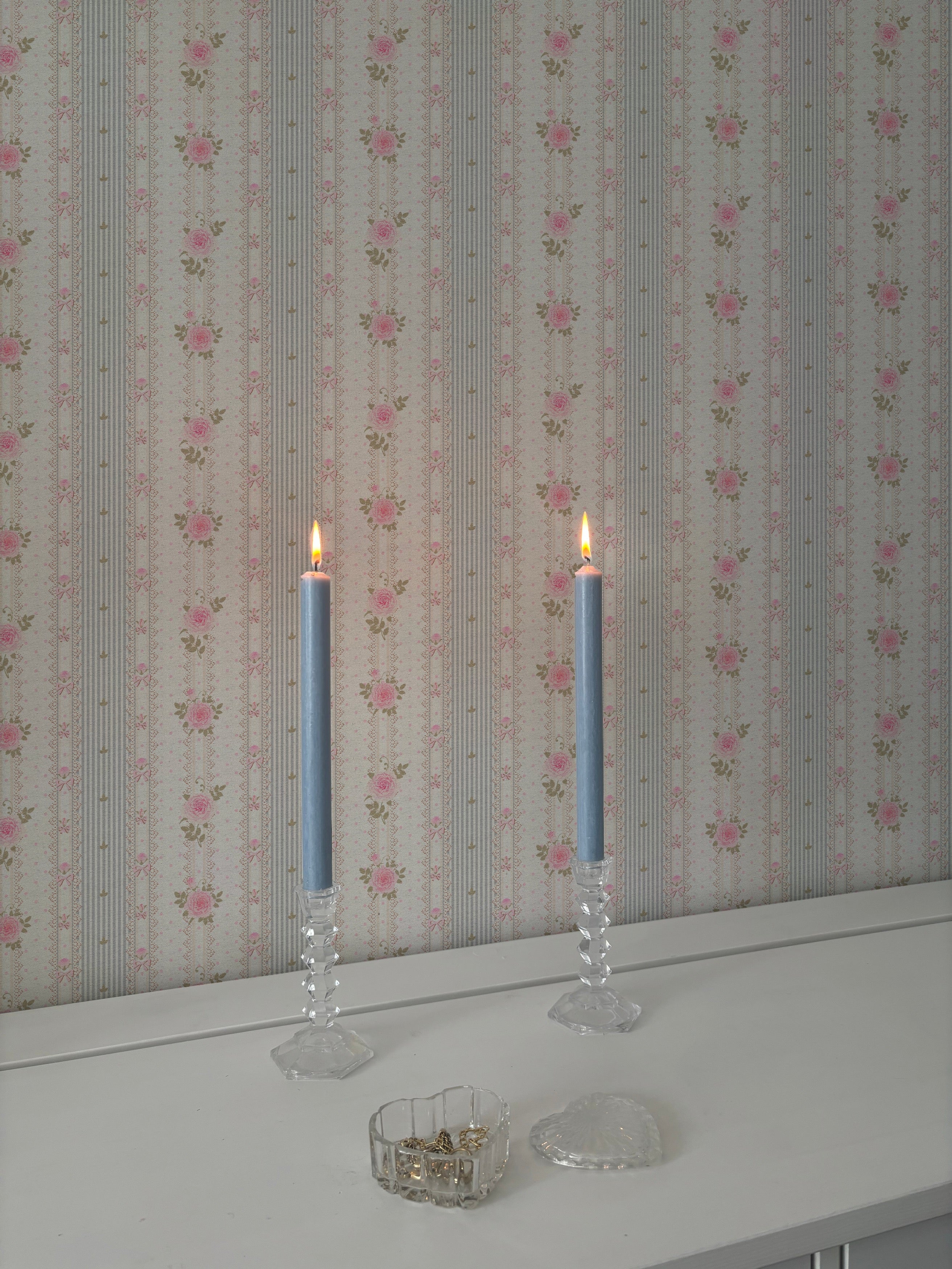 Elegant dining or workspace showcasing Vintage Cutie Wallpaper with pink rose stripes, accented by lit candles in tall crystal holders and a clear glass ashtray, reflecting a refined, classic decor style