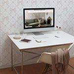 A home office space decorated with Delicate Watercolour Bows Wallpaper. The light and airy bow pattern provides a subtle yet stylish backdrop for a modern white desk and computer setup, enhancing productivity with its clean and calming vibe.
