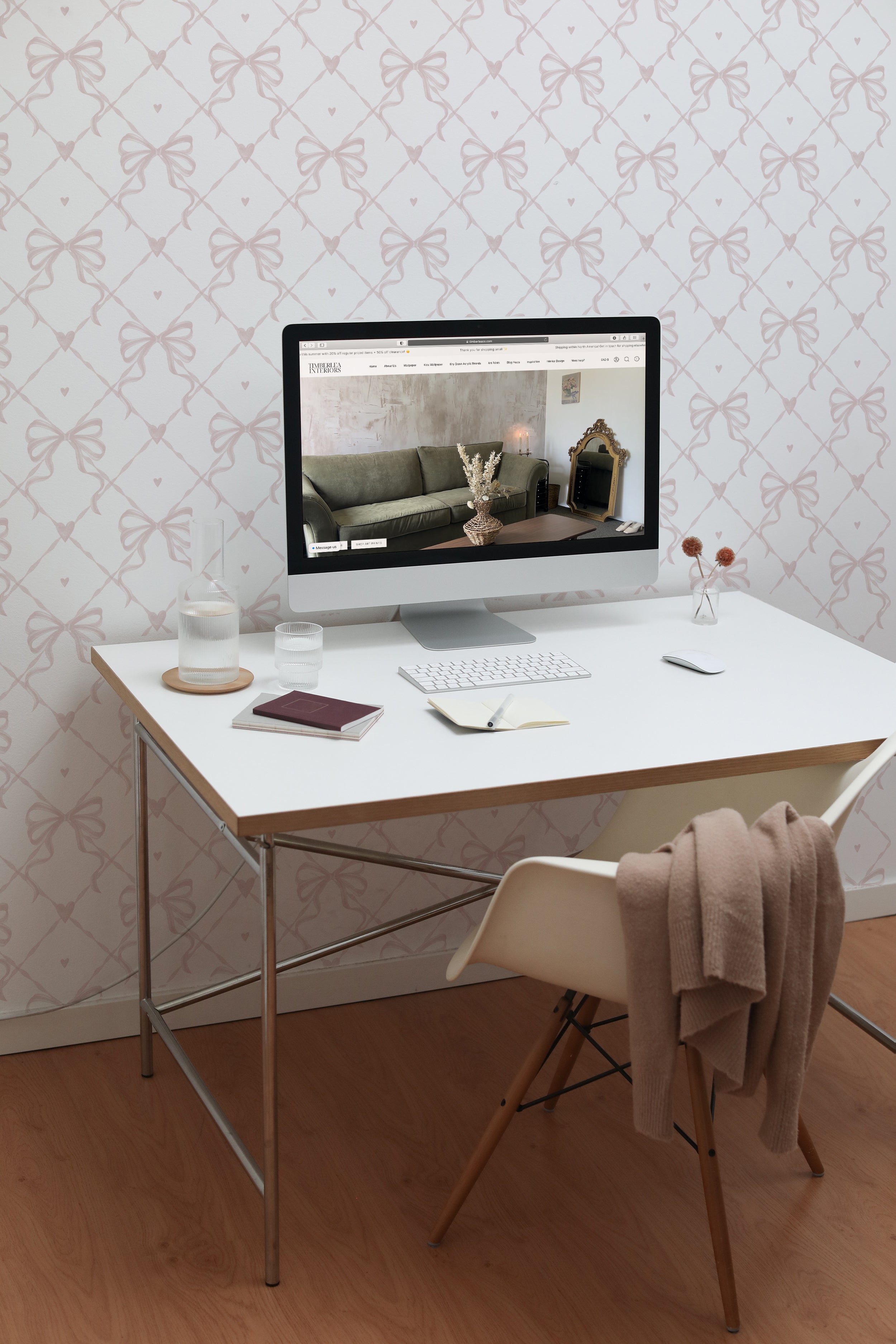 A home office space decorated with Delicate Watercolour Bows Wallpaper. The light and airy bow pattern provides a subtle yet stylish backdrop for a modern white desk and computer setup, enhancing productivity with its clean and calming vibe.