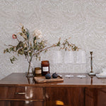 An elegant sideboard against the 'William Bough Wallpaper', decorated with a dried flower arrangement, glassware, and select kitchen items for a rustic-chic look
