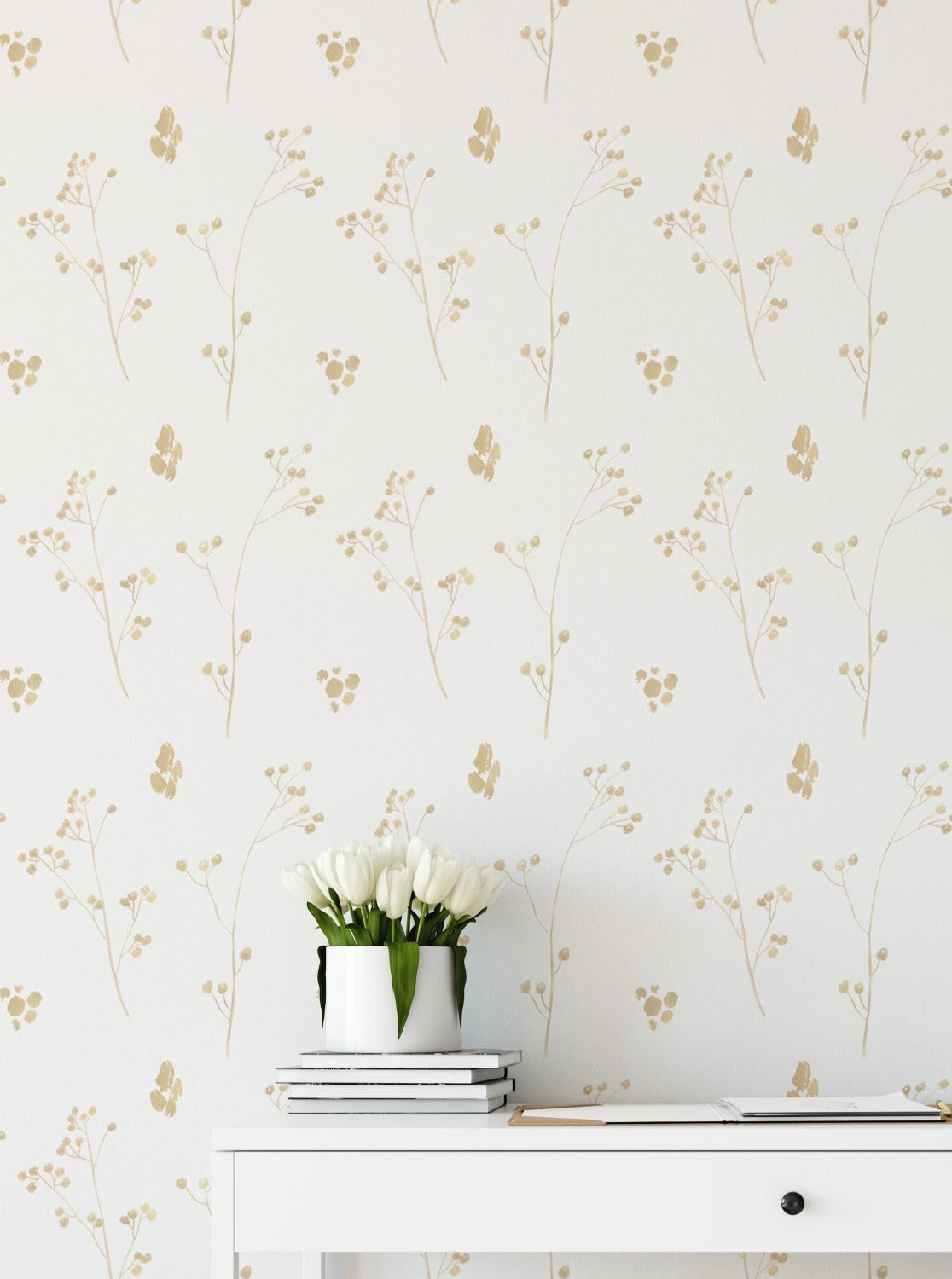 A sophisticated home office setup showcasing the Gold Collection Wallpaper III, with its understated golden floral pattern providing a luxurious backdrop to a clean, white desk and chair, accented by a bouquet of white tulips and a minimalist desk lamp.