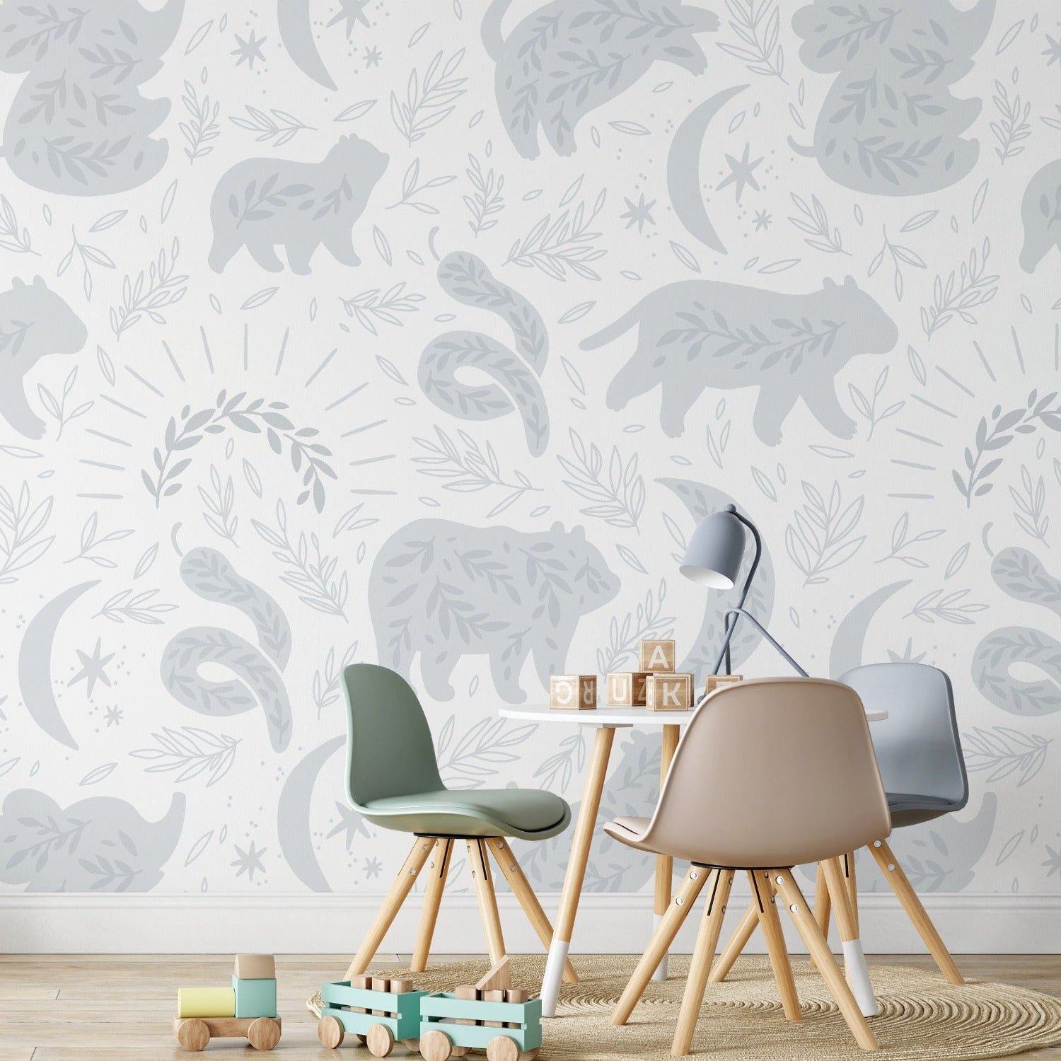The Big Kids Boho Wallpaper creates an enchanting backdrop in a child's play area, featuring pale blue forest creatures and celestial motifs amongst foliage. The gentle hues and bohemian design inspire calm and creativity in the room.