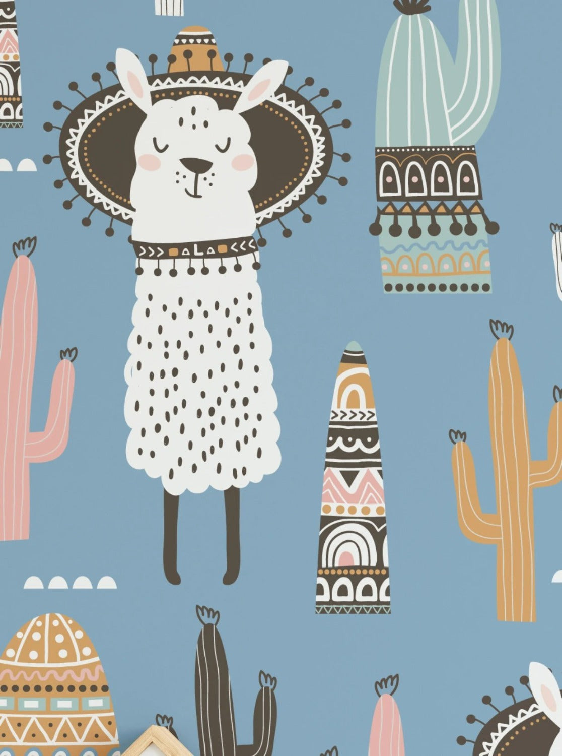 Whimsical llama illustration in festive attire on light blue background with cacti and tribal motifs.