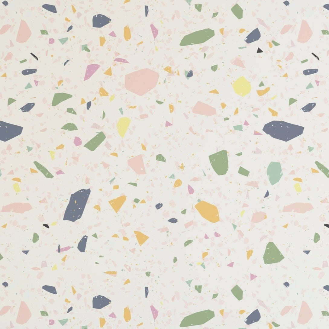 An image showcasing a section of pastel terrazzo wallpaper with a variety of scattered, abstract shapes in muted shades of pink, yellow, green, and dark blue on a soft cream base, giving a cheerful and whimsical appearance suitable for children's spaces.