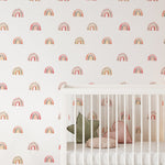 A nursery room with walls covered in Watercolor Rainbow Wallpaper, showcasing soft pastel rainbows on a clean white backdrop, creating a warm and whimsical atmosphere suitable for a child's room.