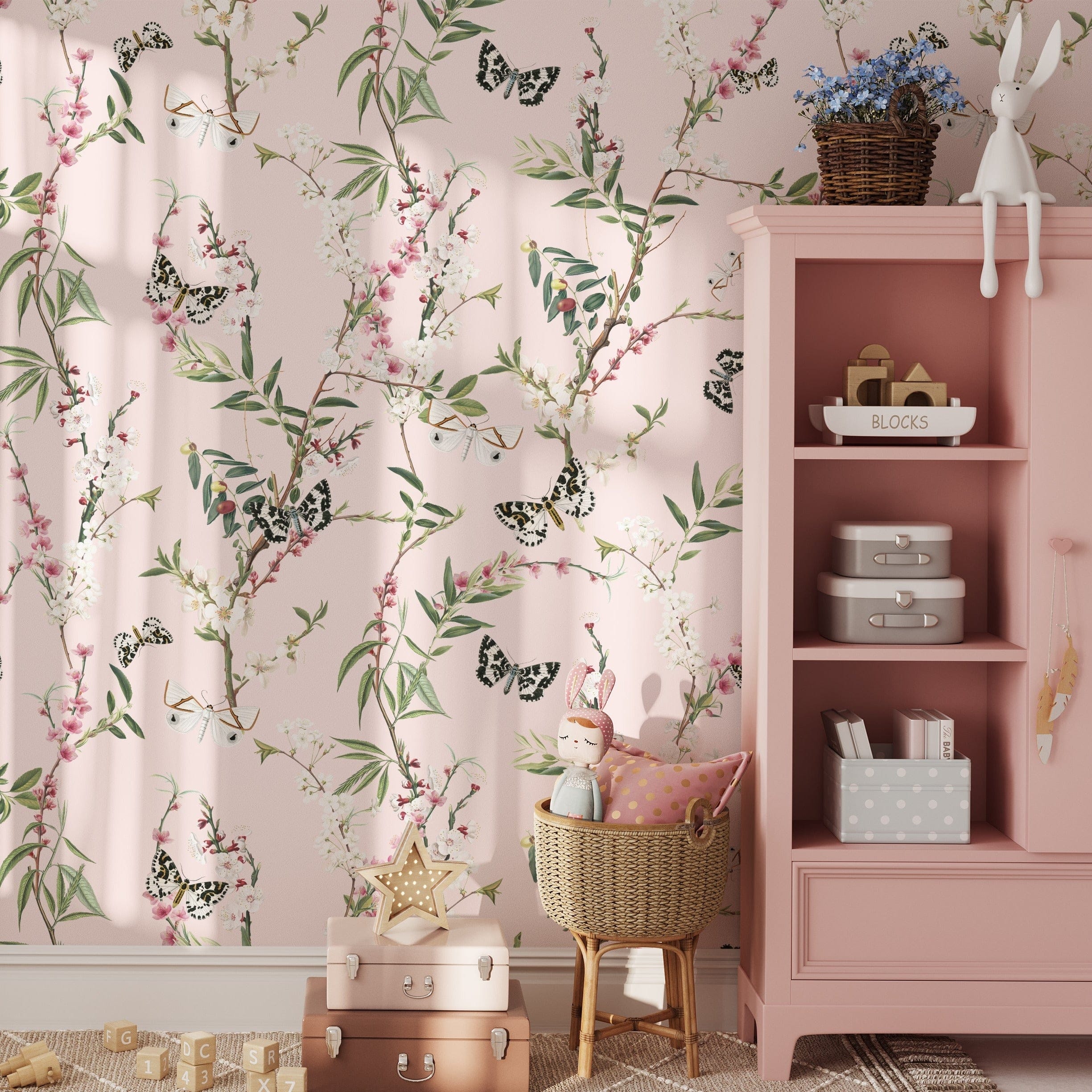 A charming children's room decorated with Enchanting Butterflies Wallpaper. The whimsical design of butterflies and blooming branches adds a playful yet elegant touch to the room, complementing the pink furniture and toys, and creating a delightful and inviting space for kids.