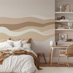 Modern Landscape Wall Mural Wallpaper featuring abstract wavy lines in neutral tones of beige, brown, and cream, creating a serene and calming atmosphere in a bedroom with a neatly made bed and a cozy workspace