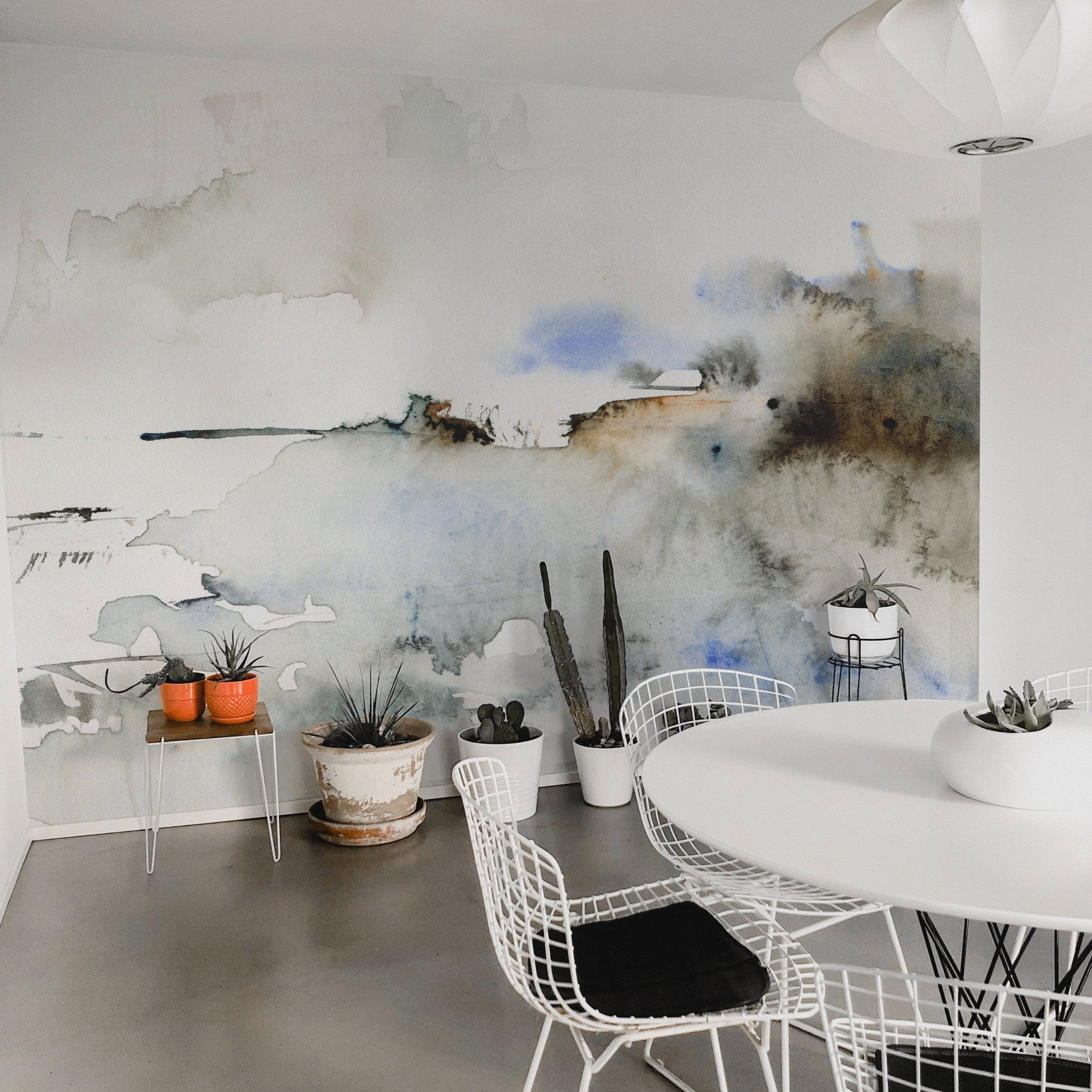  An intimate setting featuring the "Atmospheric Mural" in a cozy dining nook. The mural's abstract watercolor strokes in muted tones provide a tranquil backdrop, adding depth and character to the space while blending seamlessly with modern furniture and natural light.