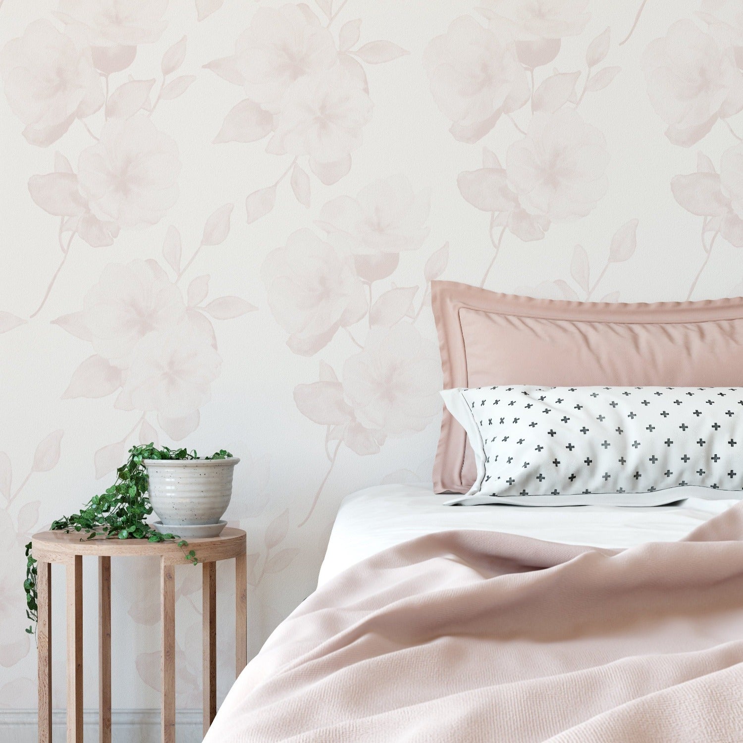 This photo depicts a bedroom interior dressed with the Minimal Floral Wallpaper V on the wall. The wallpaper adds a subtle, elegant touch with its watercolor blush flowers complementing the pastel bedding and wooden bedside table.