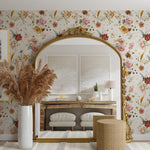 A stylish room interior with a large arched mirror framed in gold. The wall behind is adorned with Garden Flower Wallpaper III featuring a vibrant pattern of assorted colorful flowers on a light background. In front of the mirror is a modern console table with decorative items and a vase of pampas grass.