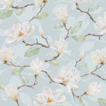 A close-up view of the 'Watercolour Magnolia Wallpaper II', where the artistry of the watercolor technique is evident in the soft brush strokes on the white magnolia flowers with hints of yellow at the center, set against a calming blue background, giving a touch of nature's elegance to any room.