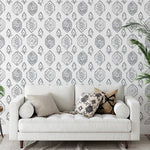 A stylish living room with one wall adorned with the Moroccan Tile Wallpaper IX, complementing the contemporary decor including a white couch with patterned cushions, a tall indoor plant, and elegant drapery.