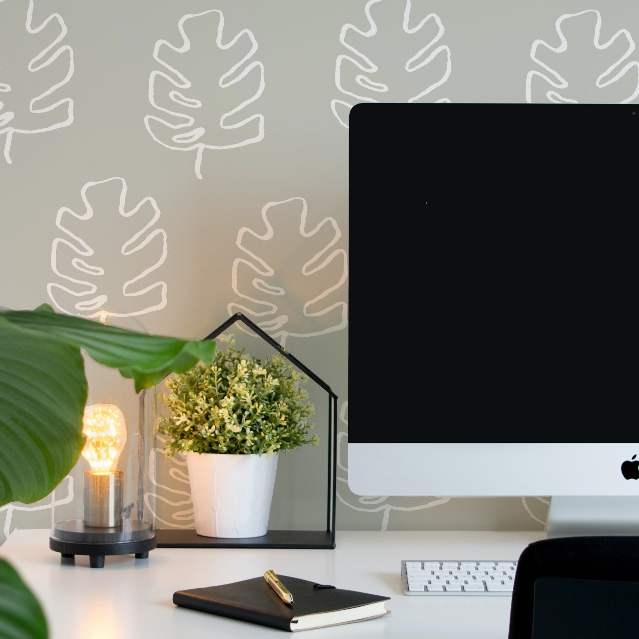 A stylish home office setup enhanced by the Palm Leaves Wallpaper, featuring a simple and elegant white palm leaf design on a grey backdrop. The wallpaper adds a touch of nature-inspired tranquility to the space, complemented by a modern desk and ambient lighting.