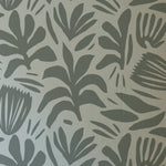 A detailed view of the Night Train Abstract Floral Wallpaper, featuring a bold, monochromatic design of stylized leaves and floral motifs in varying shades of gray, set against a light gray background.