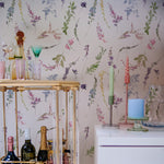 Spring Fling Wallpaper in a chic home bar setting with elegant glassware, colorful candles, and various bottles, highlighting the delicate floral design in soft watercolor tones