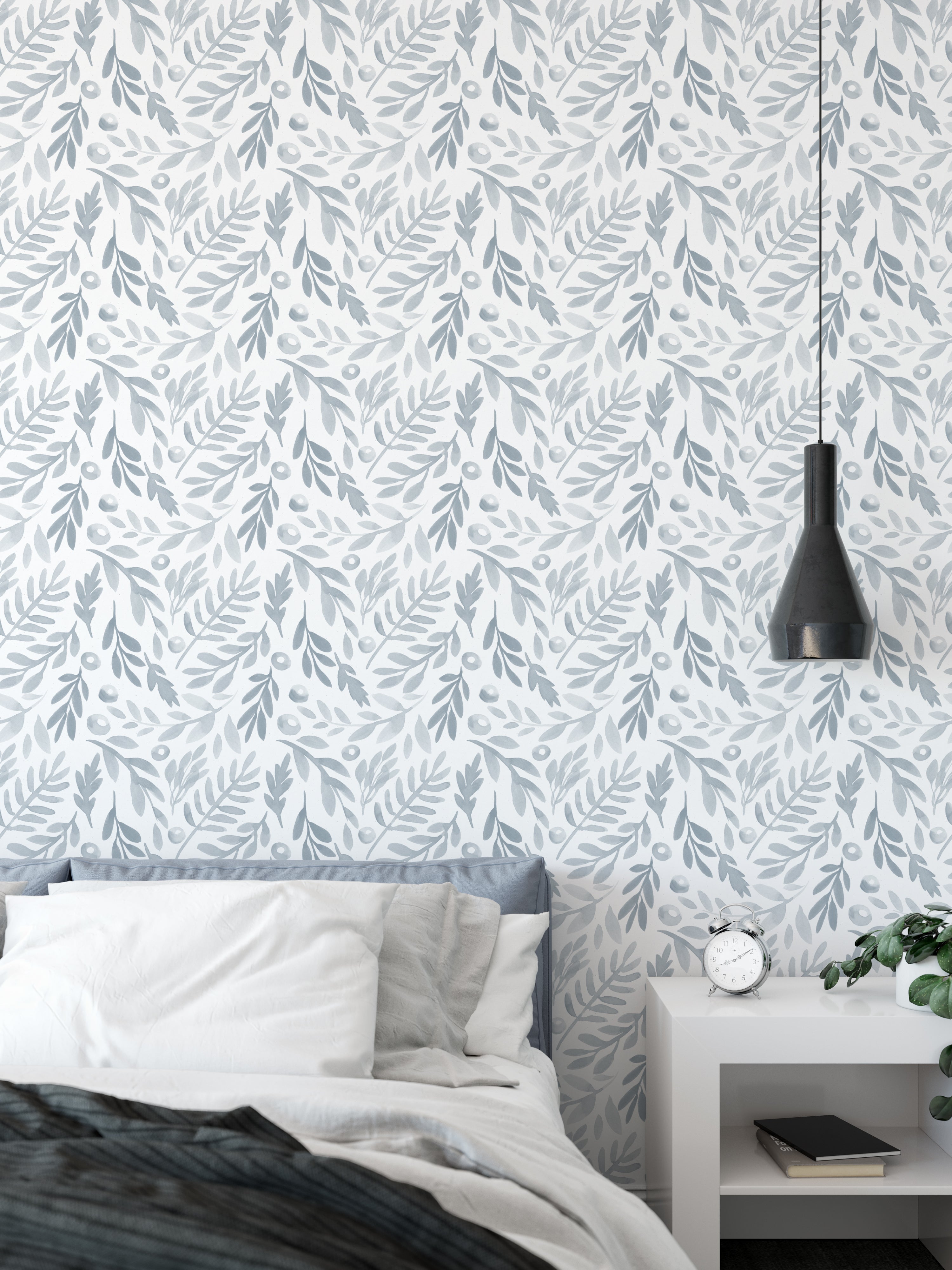 A bedroom setting adorned with 'Watercolor Subtle Botanica - Pale Blue' wallpaper that brings a soothing ambiance to the room. The pale blue leafy design pairs well with the minimalistic bedroom furniture, enhancing the peaceful and restful environment.