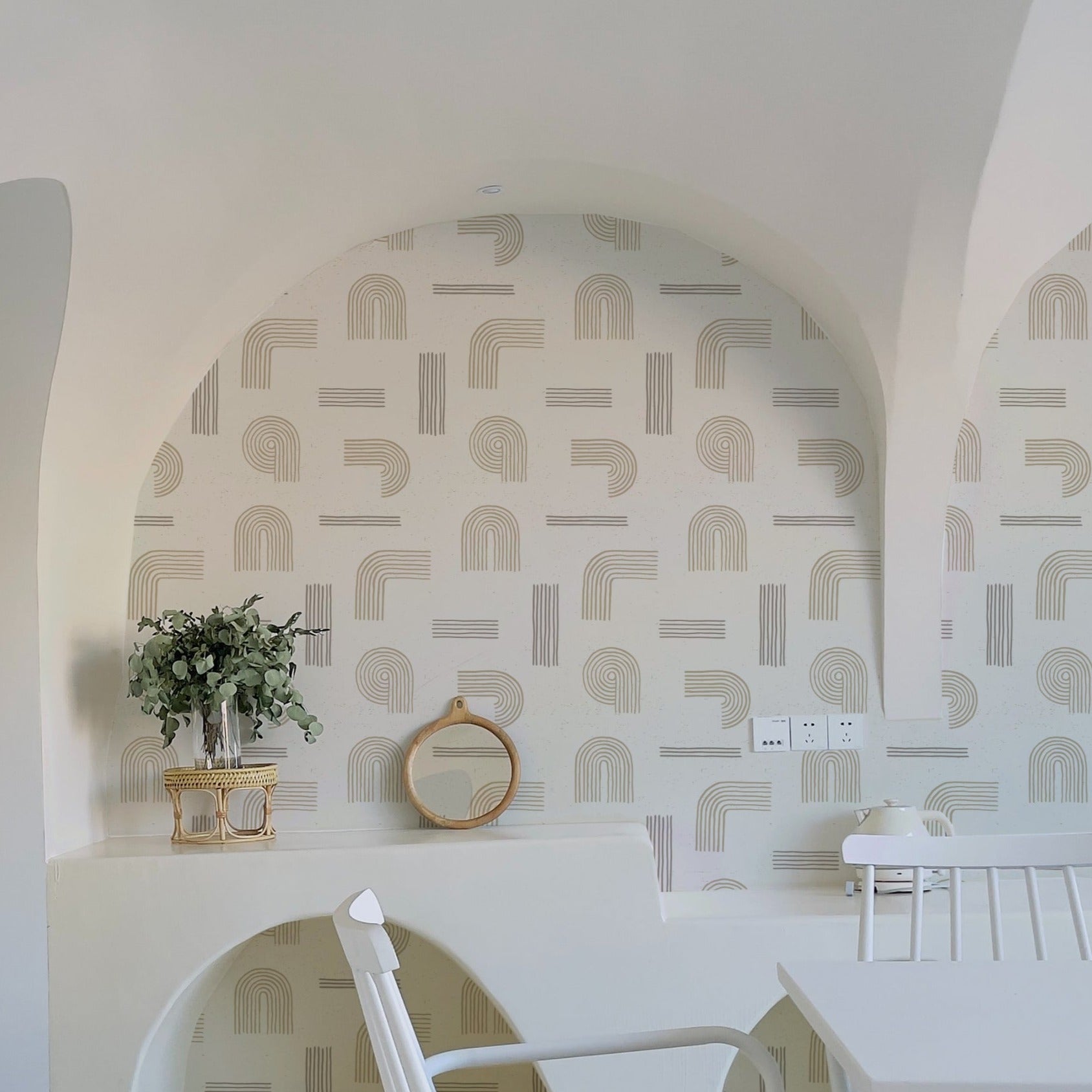 A bright and airy room decorated with Sand Zen Geometric Wallpaper - VII on the walls, complemented by white furnishings and natural wood accents. The space is styled with minimalist decor, including a white arch-shaped mirror and a small plant, creating a serene atmosphere.