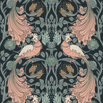 Close-up view of the Peacock Damask Wallpaper showcasing the intricate pattern of stylized peacocks with flowing tails and detailed floral elements in shades of pink, green, and beige on a dark background.