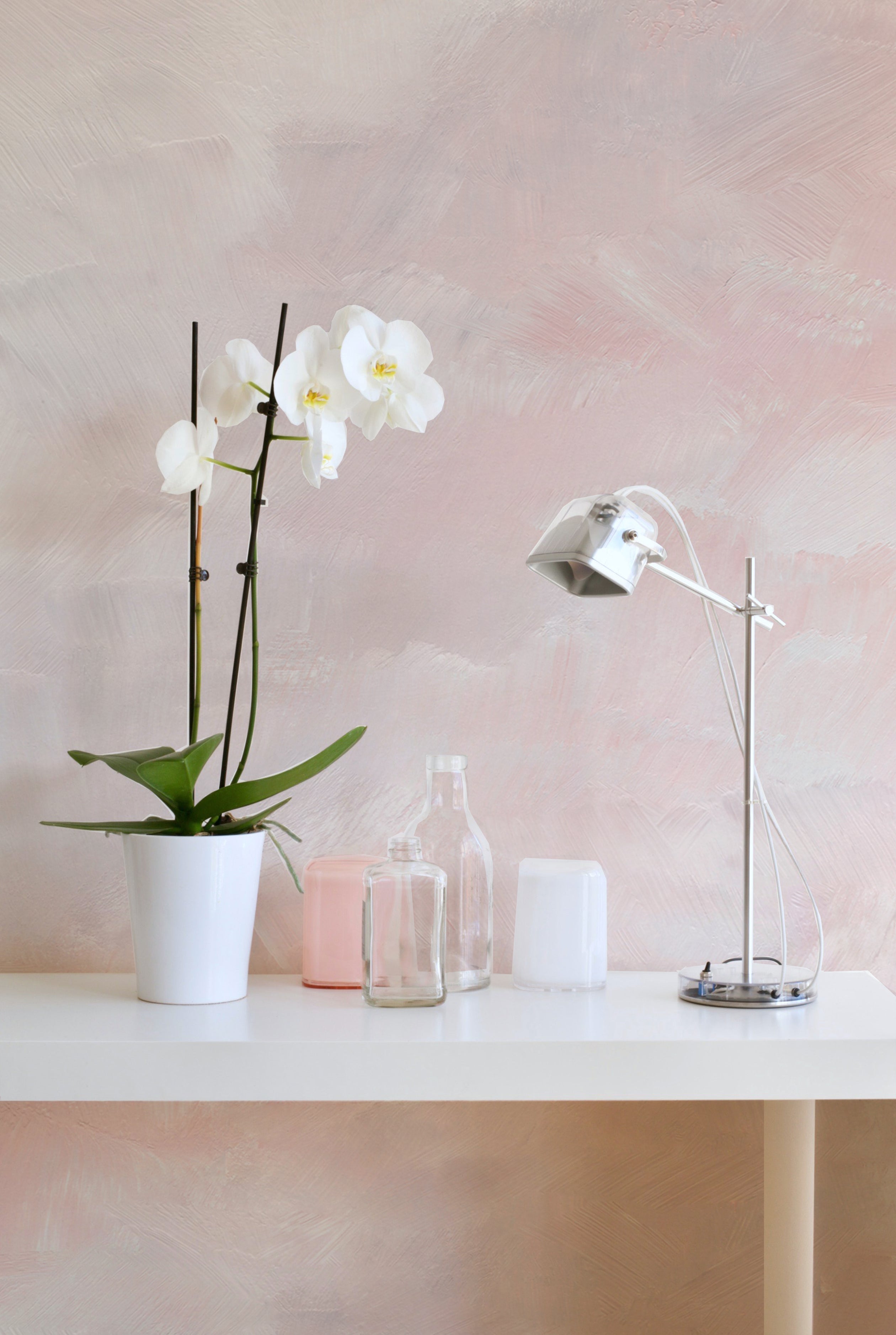 An elegant workspace accented by the Venetian Watercolor Wallpaper, providing a calming background for a white desk adorned with a potted orchid, a desk lamp, and minimalist decor.