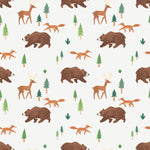 Close-up of a playful wallpaper pattern showcasing illustrated brown bears, deer, and foxes interspersed with small pine trees and green foliage. The design captures a lively forest scene in soft, earthy tones, perfect for a nature-themed nursery or children's room.
