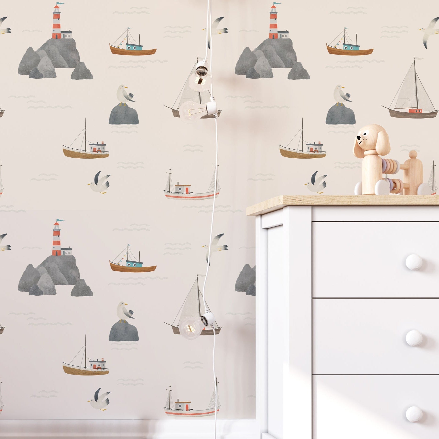 A child's room adorned with "By the Sea - Sailboat and Lighthouse Wallpaper," featuring whimsical nautical scenes that include sailboats, lighthouses, and floating sea birds. This wallpaper brings a sense of adventure and calm to the space, perfectly suiting a playful yet restful child's bedroom.