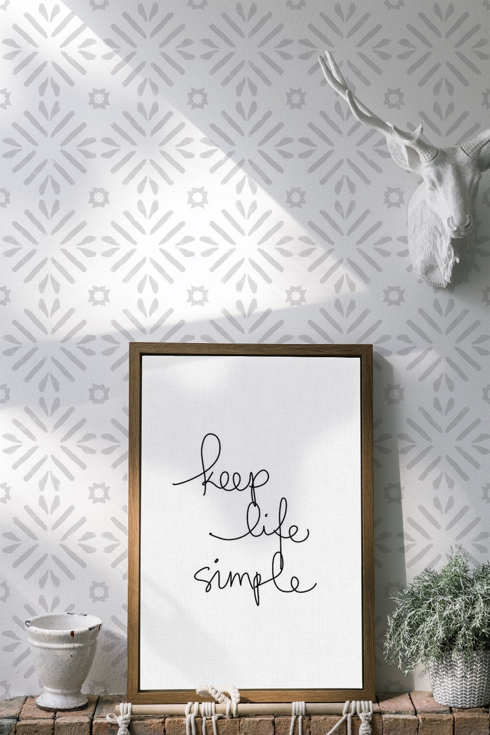 A rustic-chic interior with Geometric Wallpaper III featuring a repeating pattern of light gray stars on a white background, accented by a decorative faux deer head, a framed inspirational quote, and a woven plant holder for a blend of modern and natural elements.